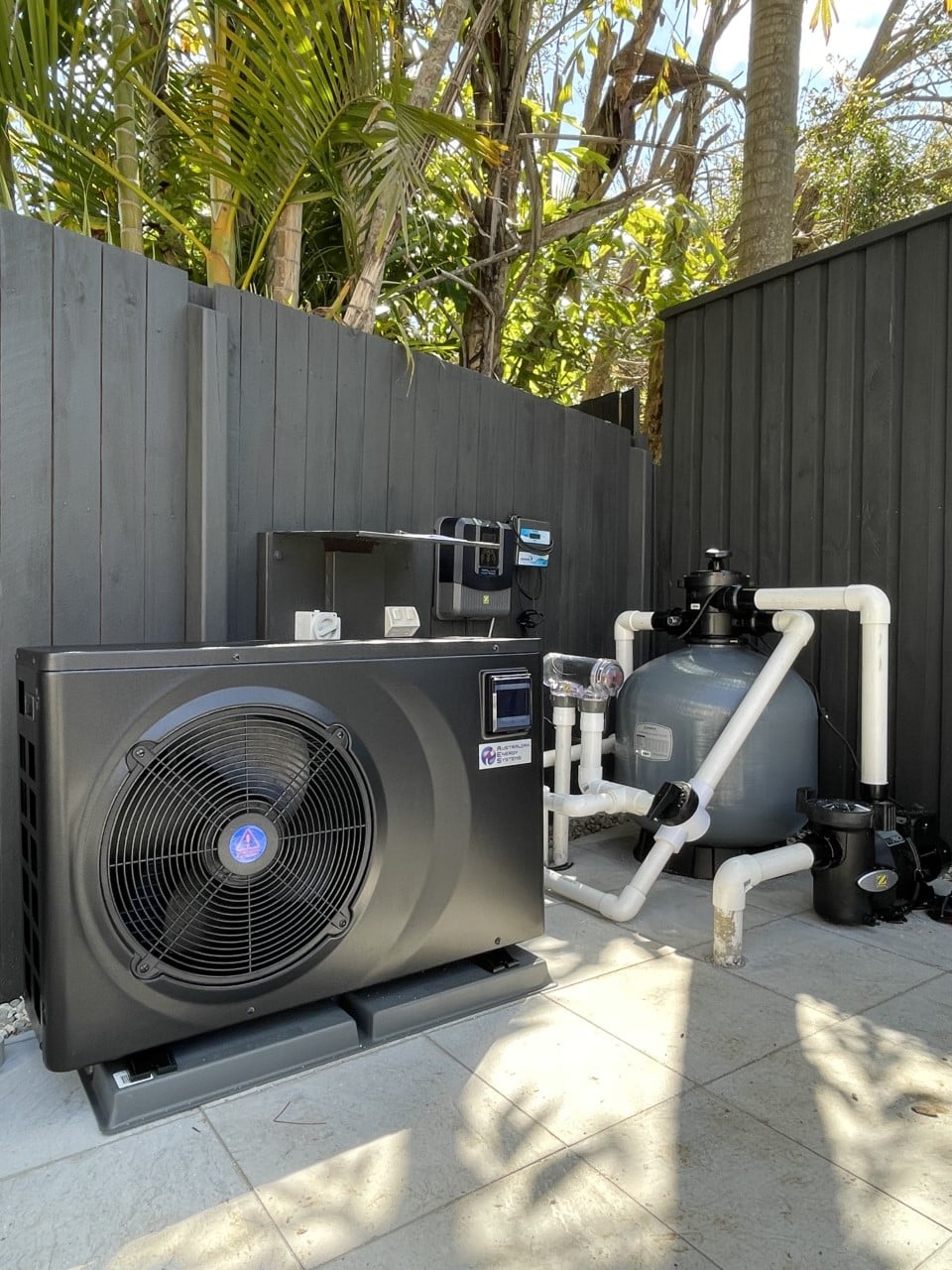 A pool heat pump unit installed beside a residential swimming pool